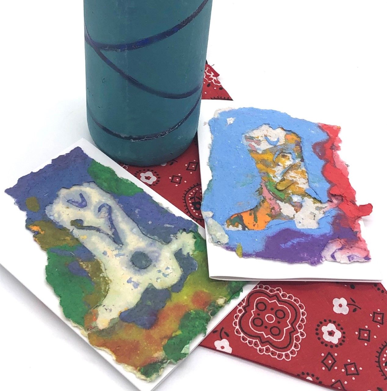 cards with pictures of cowboy boots made with handmade paper in vibrant colors sitting on top of a red bandana and a blue wine bottle in the background