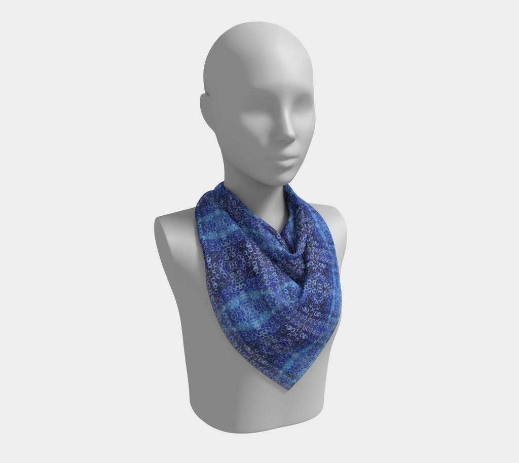 Mannequin wearing a square scarf of shades of blue and purple with light blue rings printed all over
