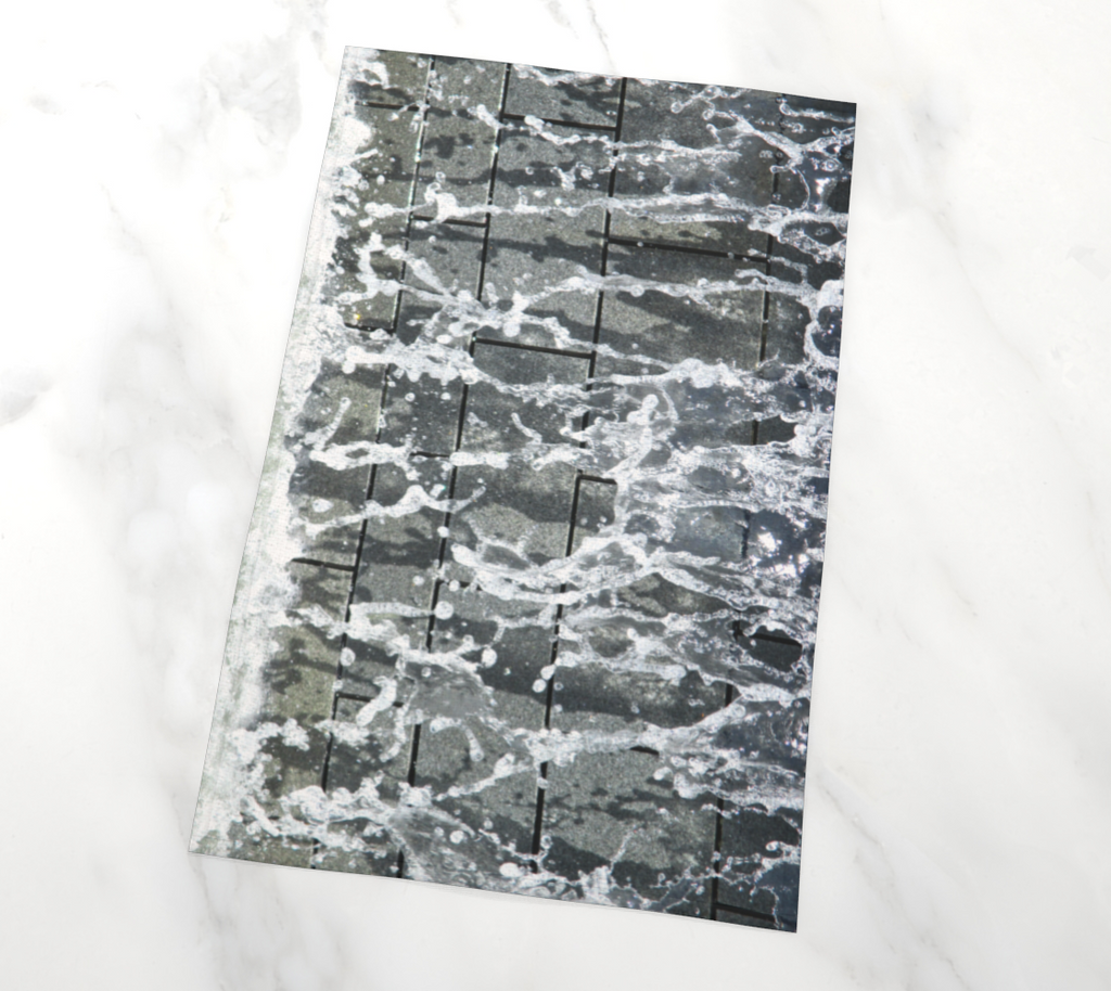 Flat lay view of tea towel with gray, white and black design depicting running water