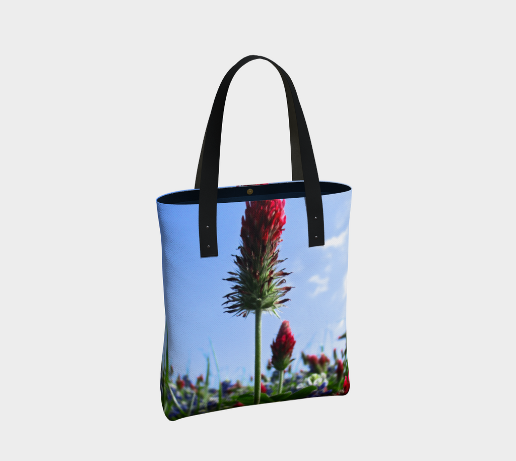 Tote bag with black double straps showing Red Indian paintbrush flowers and bluebonnets in a green field