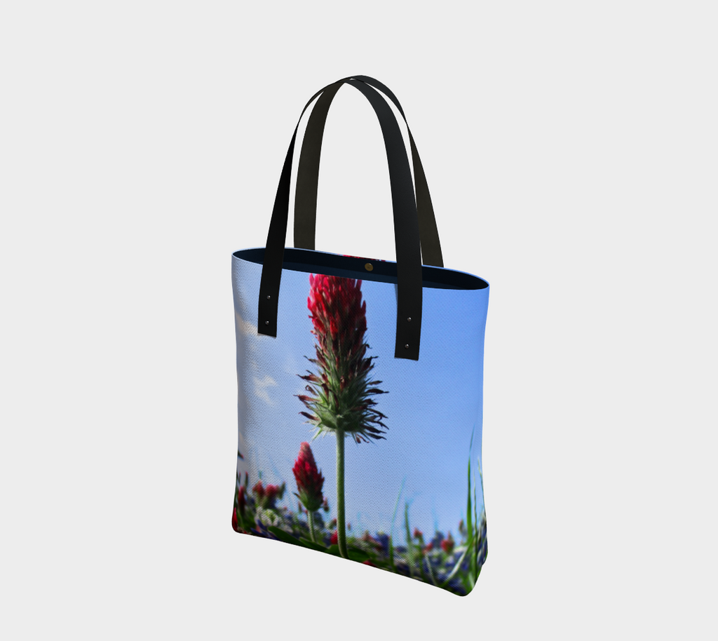 Tote bag with black double straps showing Red Indian paintbrush flowers and bluebonnets in a green field