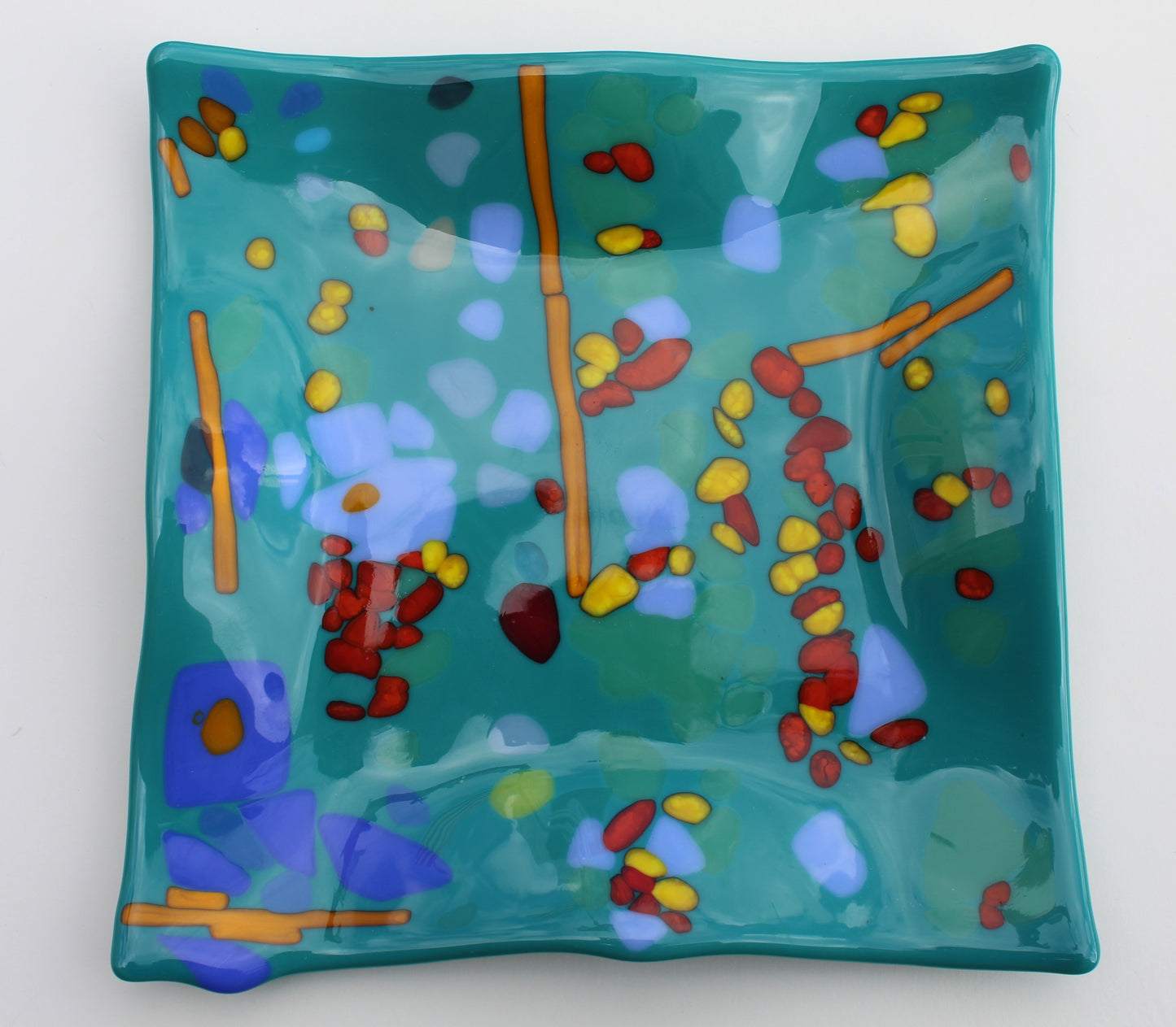 Teal glass wavy plate with accents of orange, yellow, red, and blue