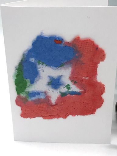 Handmade paper design on a white card.  Art paper is blue, green, and red with a small blue star inside a white star.