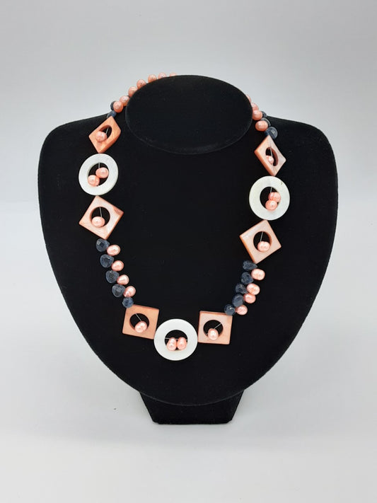 Peach and navy blue beads make up most of this necklace, with peach diamond and white circle shaped  beads through out