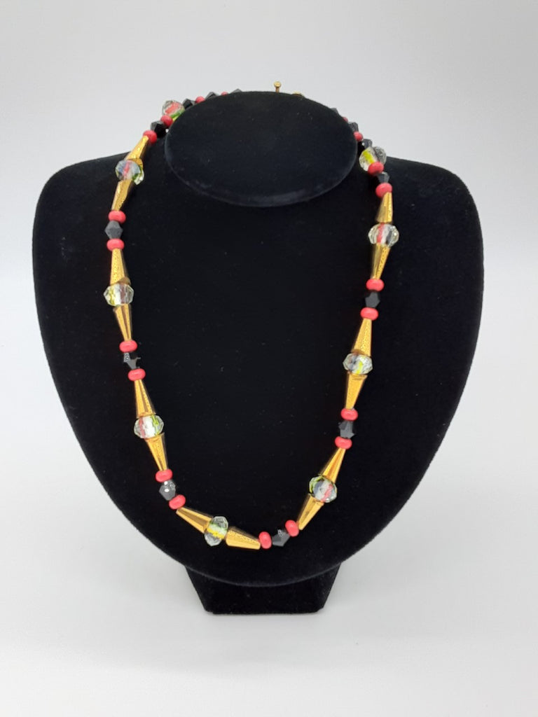 necklace of repeating beads- black, red, gold cone shaped, glass, gold cone shaped, red, and black beads