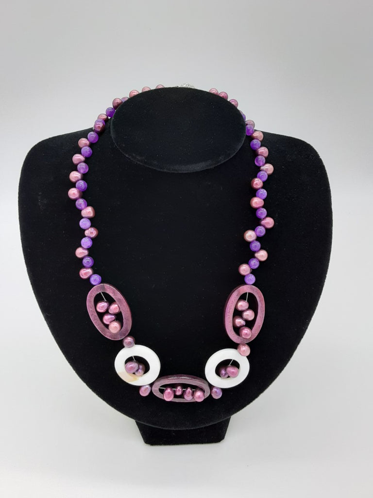 Necklace of purples- alternating with pearl and transparent purple, in the center has oval shapes with the pearls inside