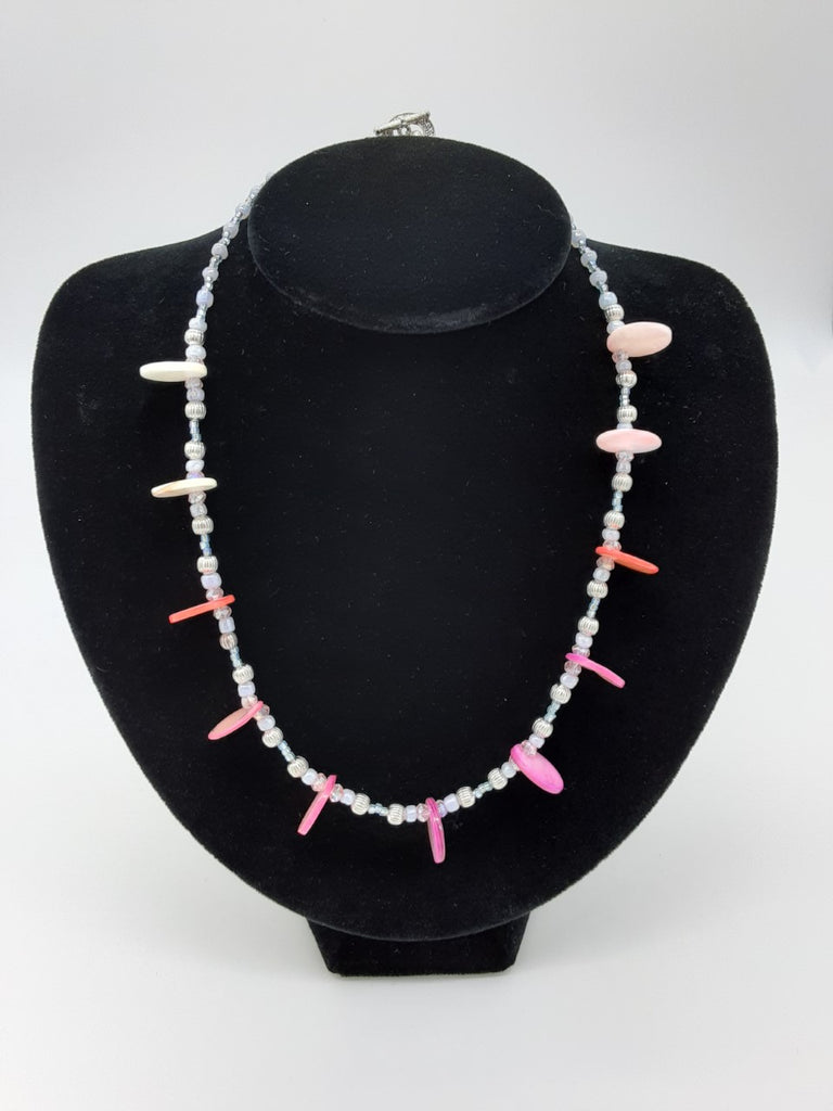 Necklace of small pale beads with circular disks of pearl in between- the color pearl is white, coral, and pink