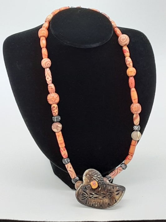 necklace with Orange decorative patterned wooden beads with a large dark brown carved center piece 