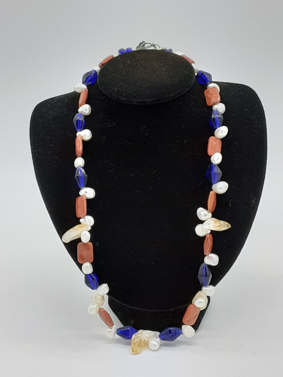Necklace with alternating beads of blue glass, brown, pearl, and quartz