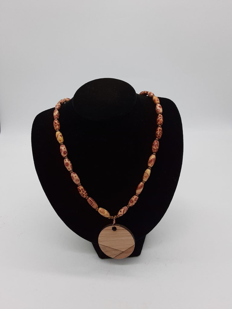 light brown necklace made with wooden beads and brass colored spacers. with a wood burned pendant