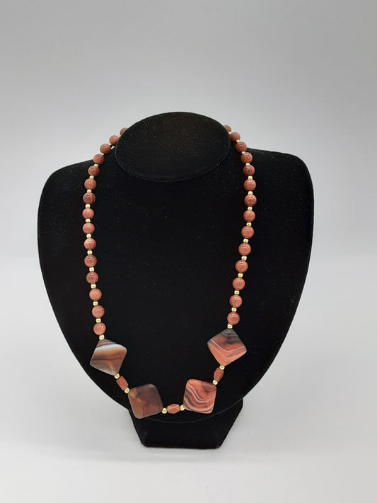 brown necklace alternating with gold beads on the edges. in the front are 4 diamond stone beads