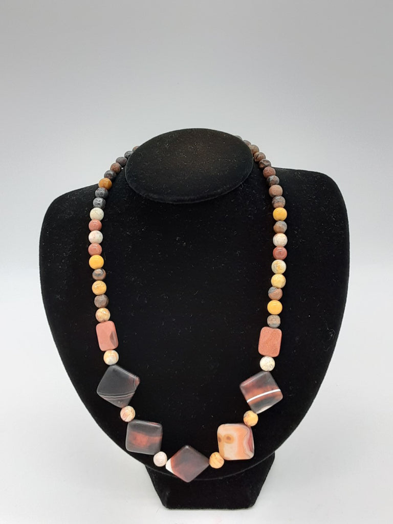 Earth colored round stones around the length of necklace with 5 diamond shaped stones in the center