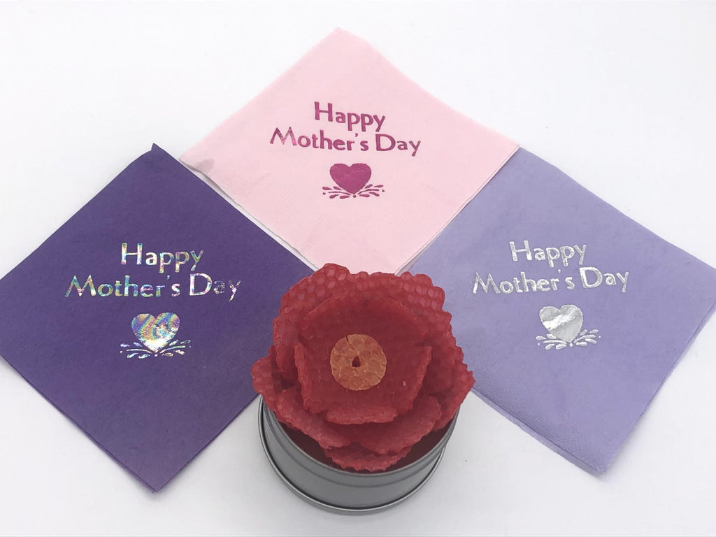 Purple cocktail napkins with iridescent Happy Mother's Day slogan, light pink cocktail napkins with dark pink Happy Mother's Day slogan, and lavender cocktail napkins with silver Happy Mother's Day slogan