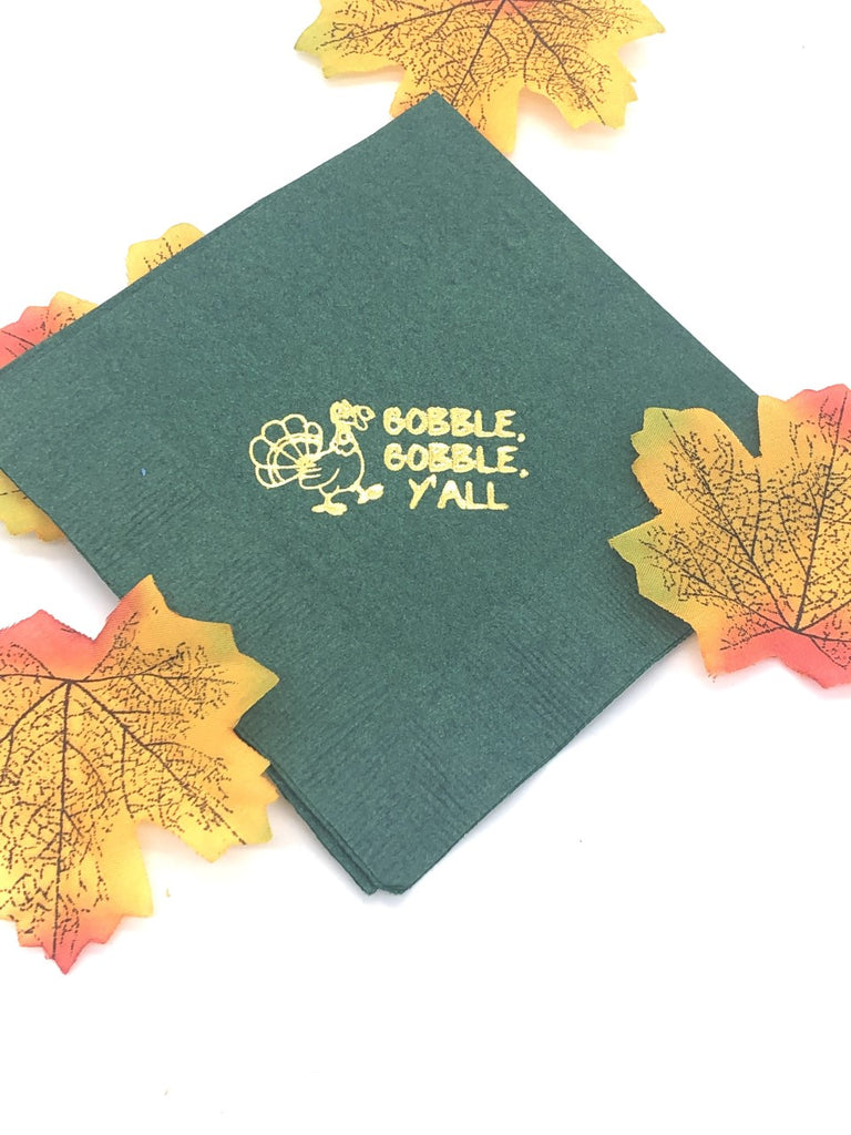 Green cocktail napkins with a gold turkey to the left of Gobble, Gobble, Y'all slogan in gold