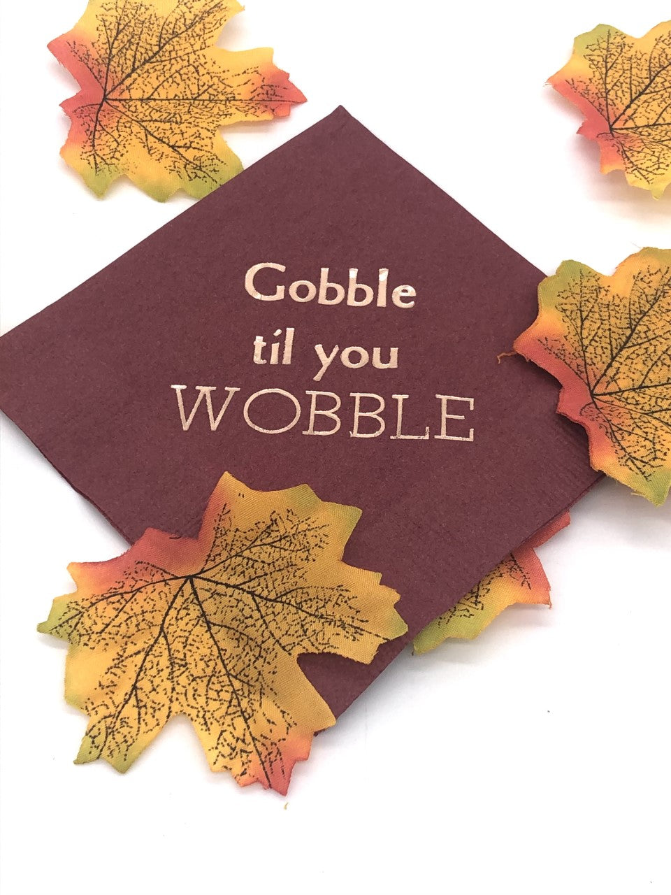 Maroon cocktail napkins with light gold Gobble til you Wobble slogan