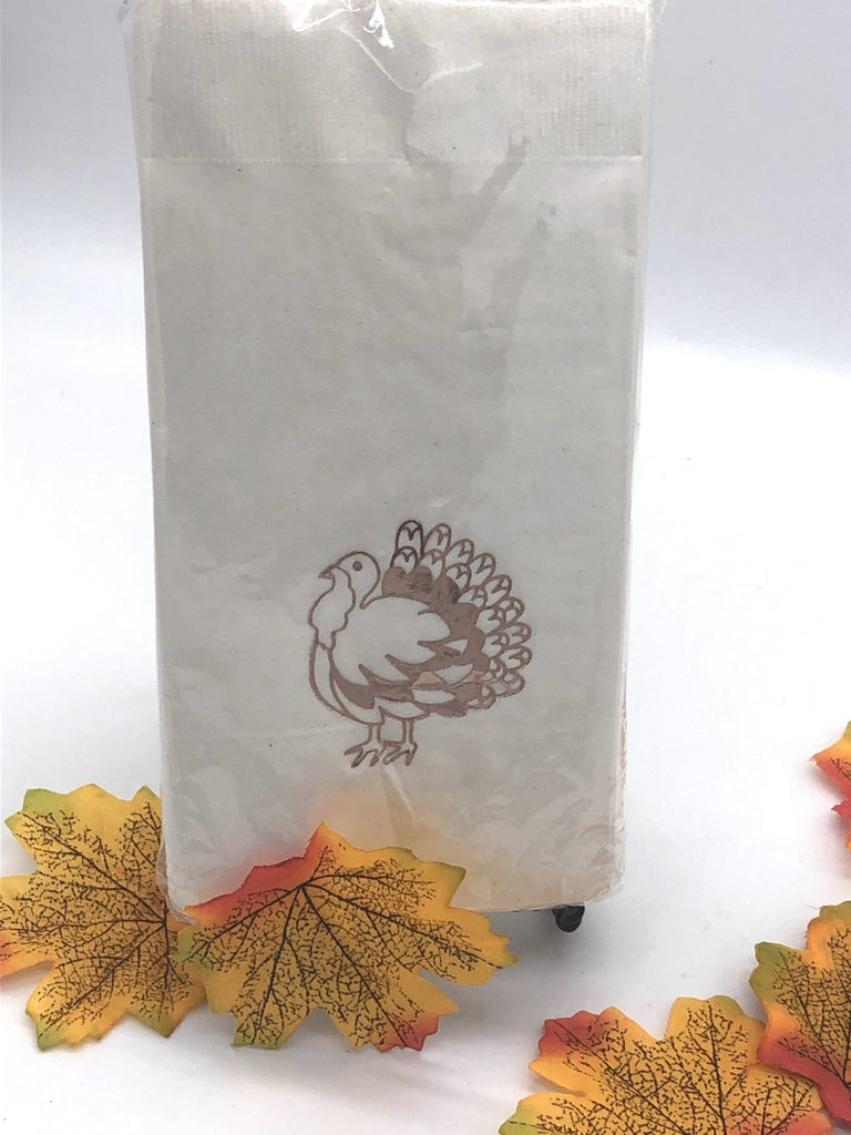 White dinner napkin with a copper foil graphic of a turkey