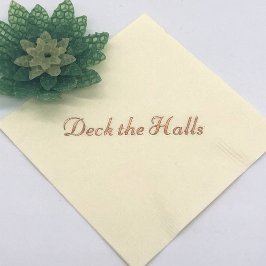 Ivory cocktail napkin with copper Deck the Halls slogan