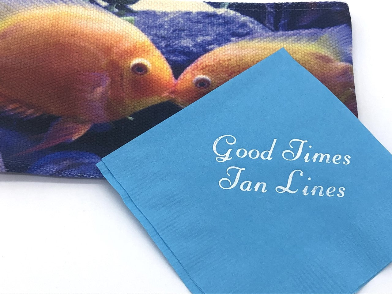 Light Blue cocktail napkin with silver Good Times Tan Lines slogan