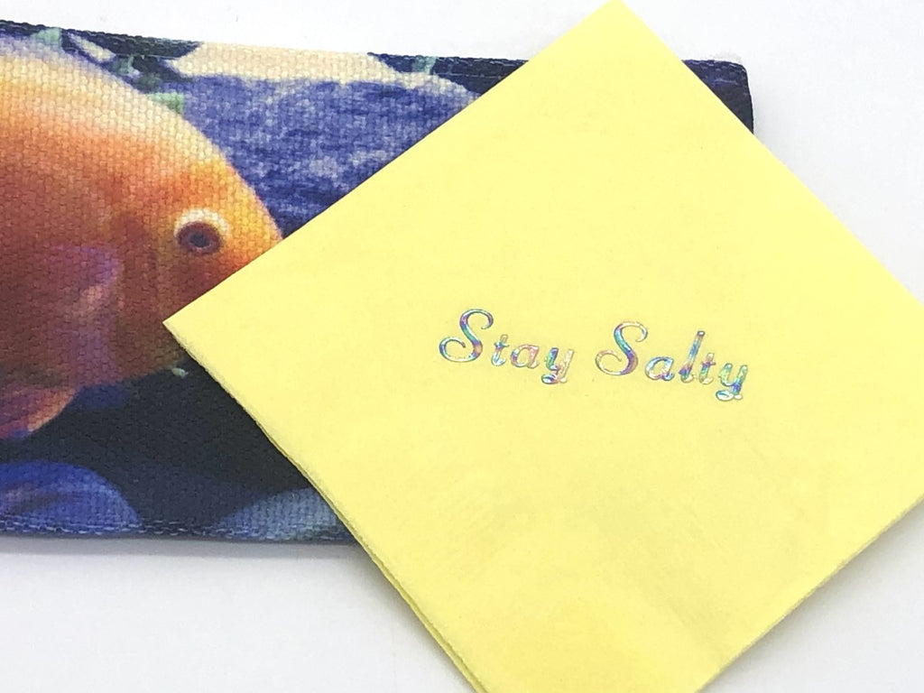 Yellow cocktail napkin with iridescent Stay Salty slogan