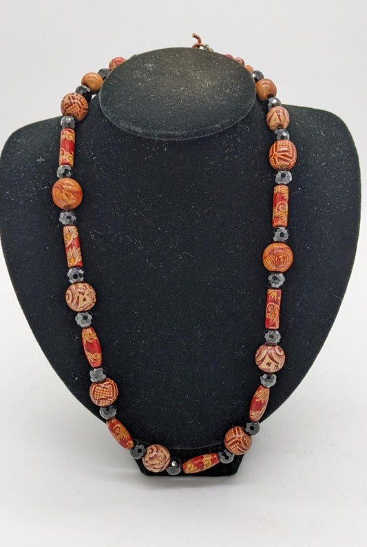 necklace of round and cylinder wooden beads with black faceted beads in between