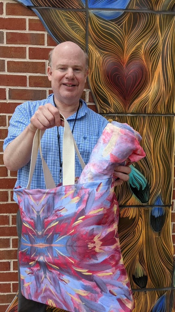 photo of artist holding up his tote and matching beach towel